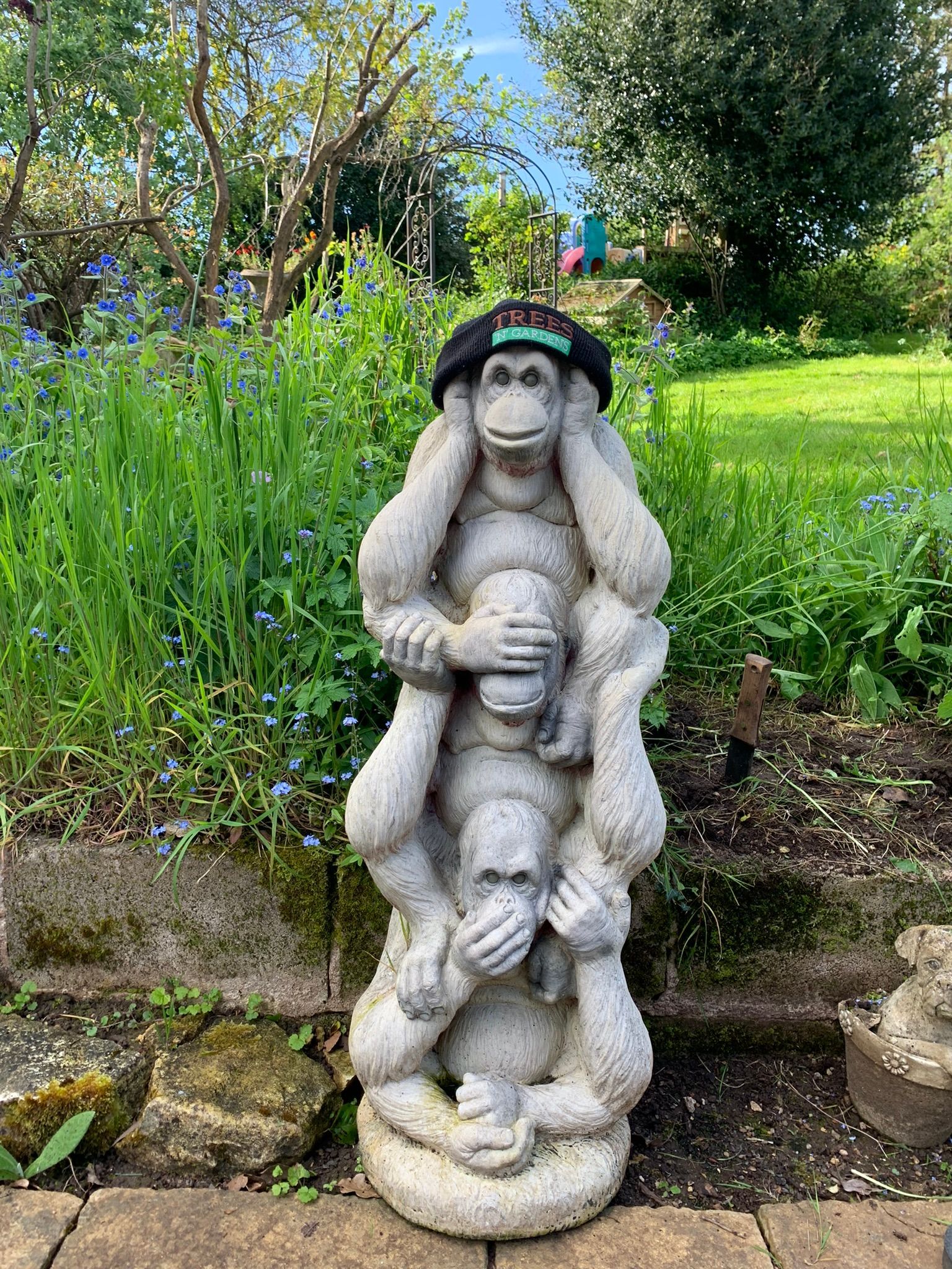 A statue of three monkeys standing next to each other in a garden.