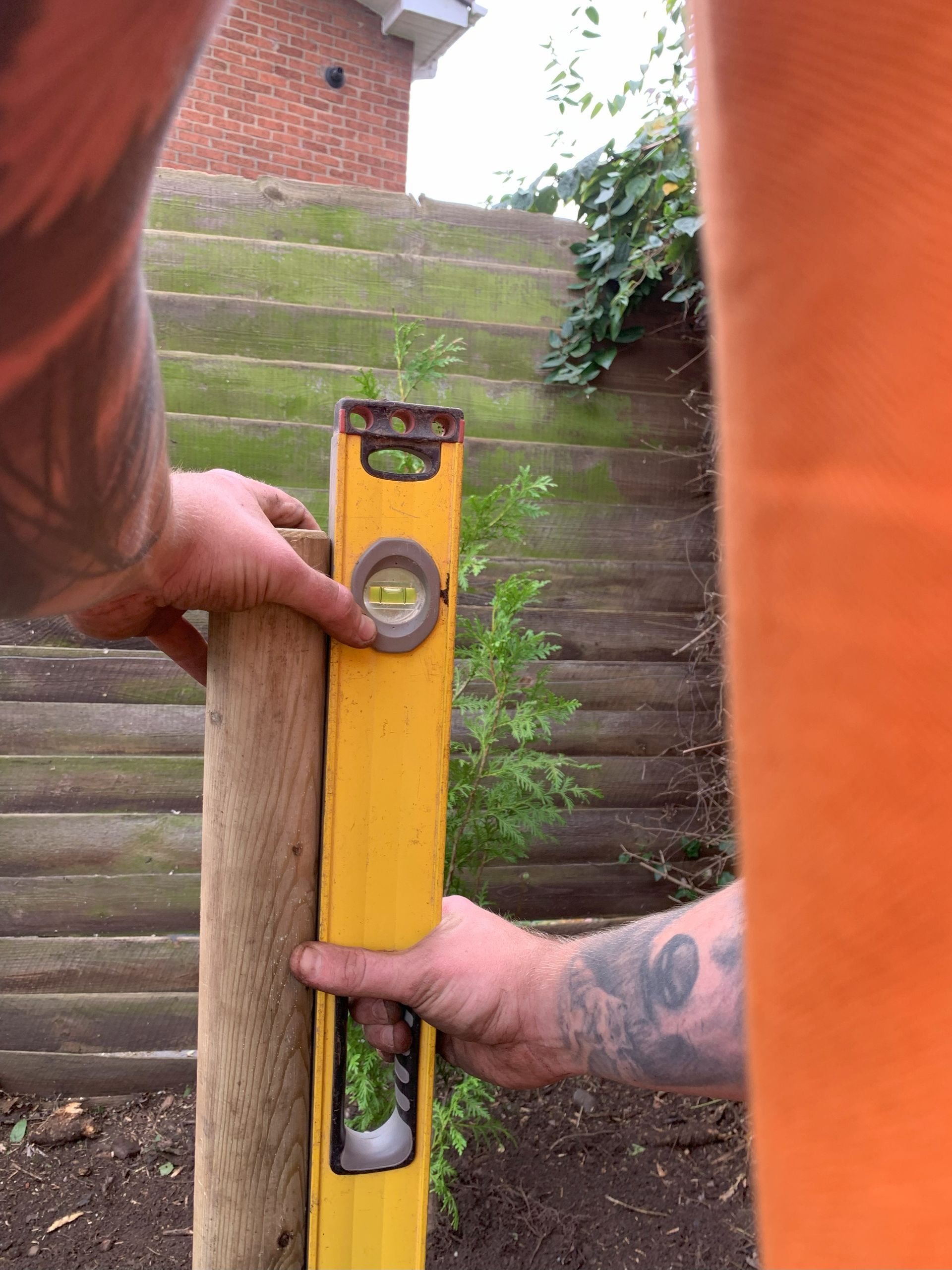 A man is measuring the level of a wooden post