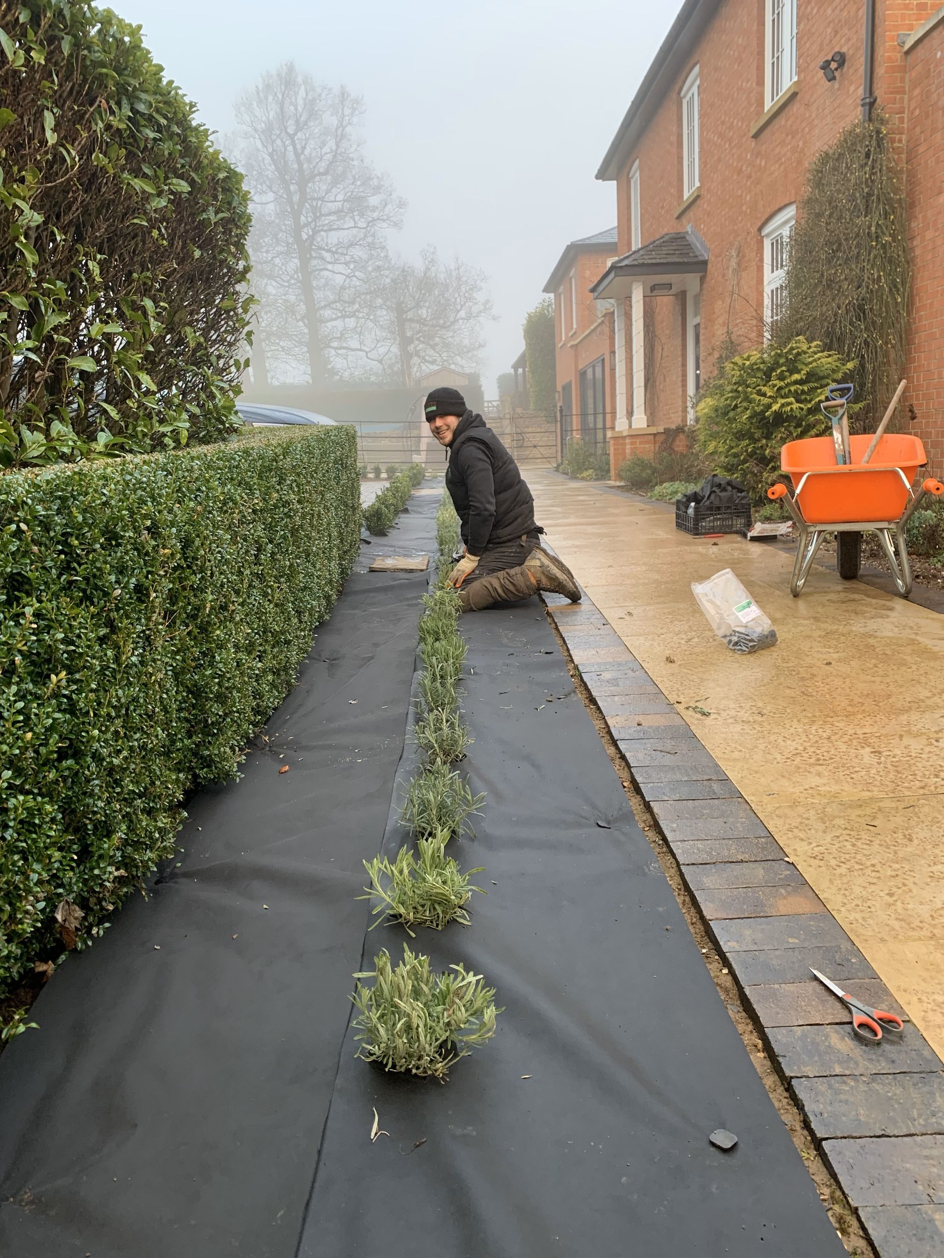 A man is kneeling down on a sidewalk next to a house.