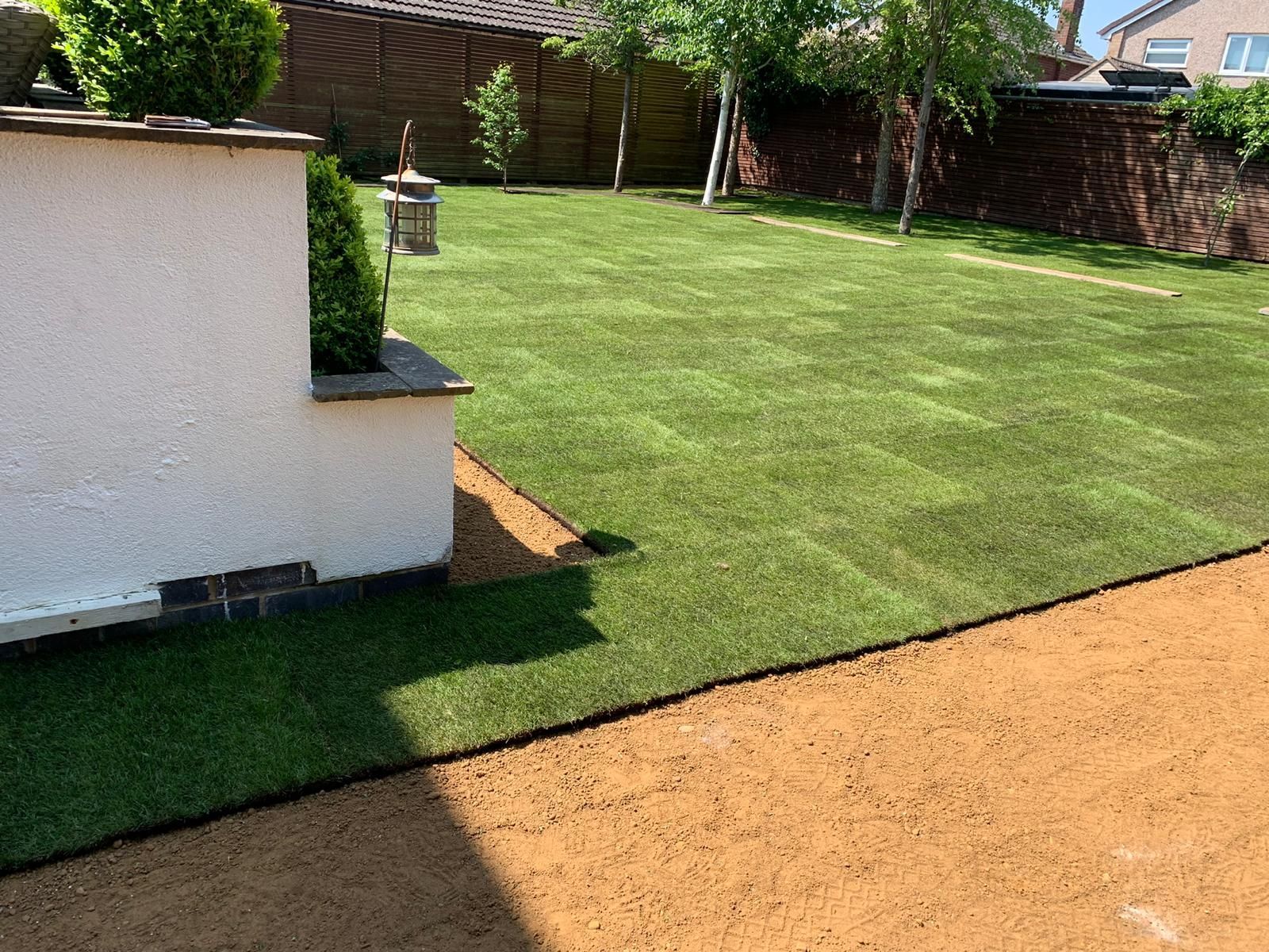 A backyard with a lush green lawn and a white building in the background.
