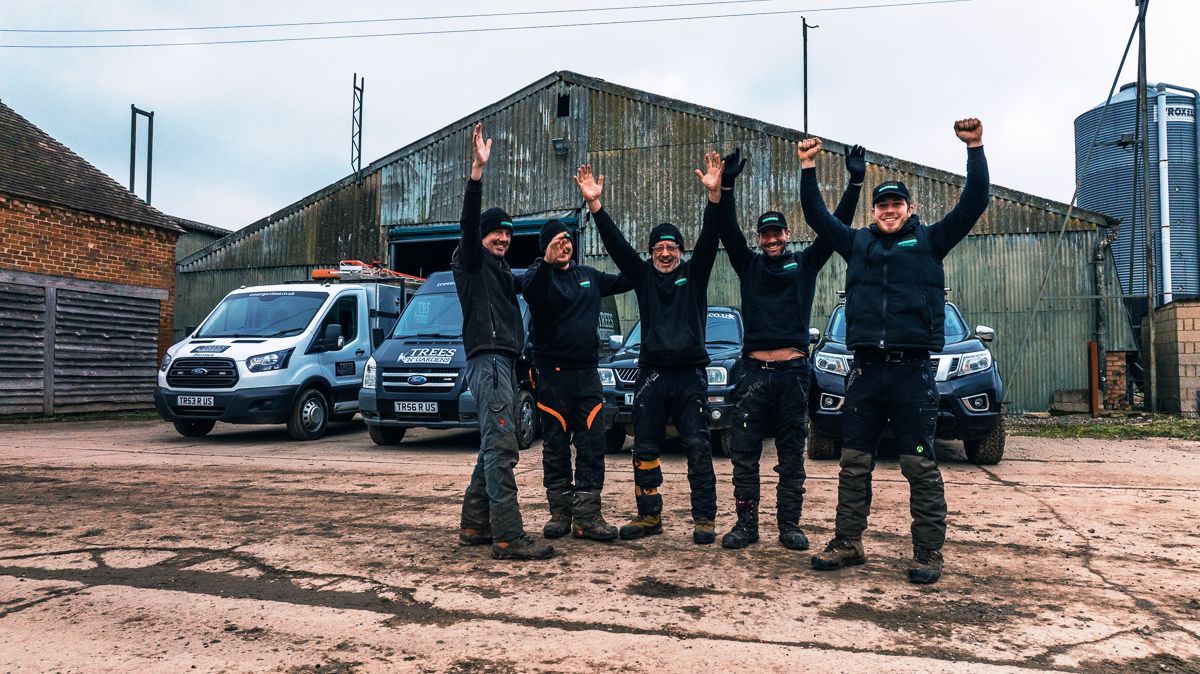 A group of men are standing in front of a building with their arms in the air.