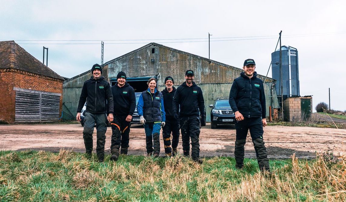 A group of men are standing in a field in front of a building.