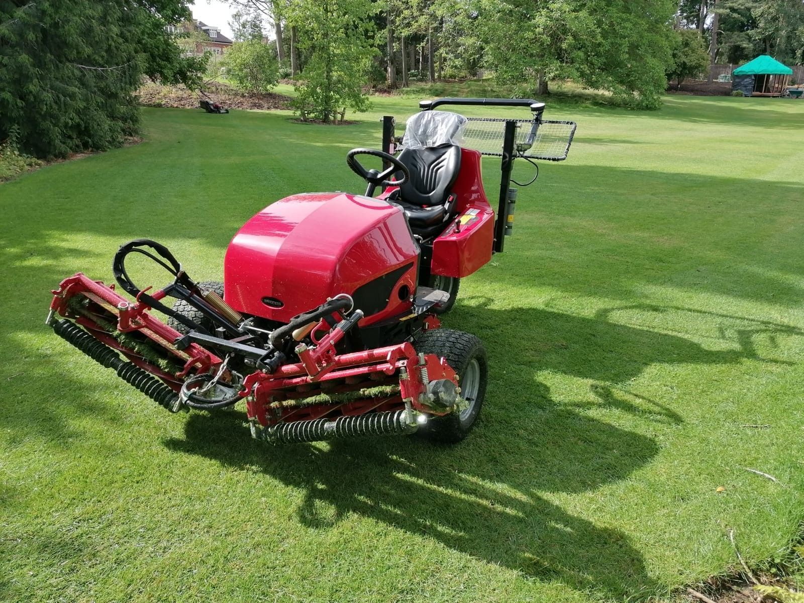 A red lawn mower is parked on a lush green field.