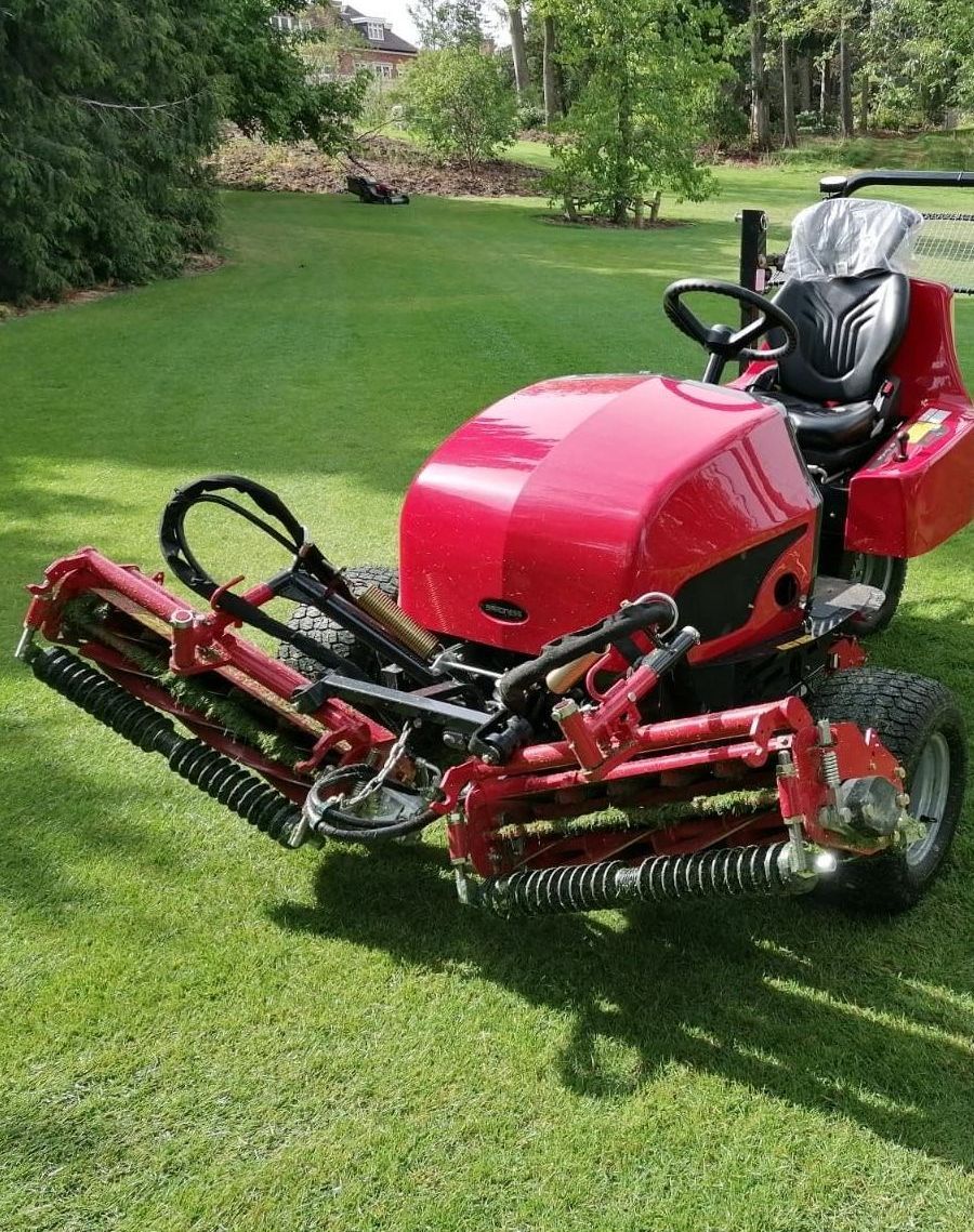 A red lawn mower is parked on a lush green lawn