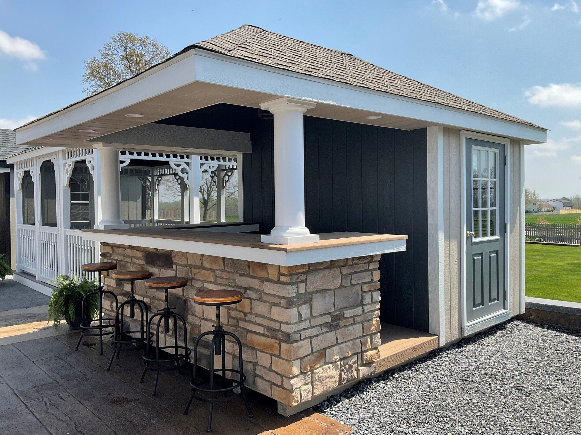 hip roof cabana with blue siding, stonework, and a bar area with barstools