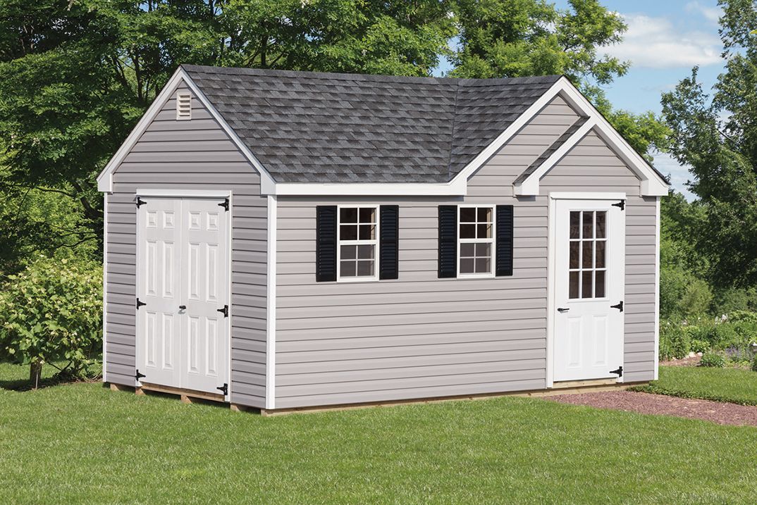 Dormer Shed with light gray vinyl siding, white trim, a set of white double doors, a white single-entry door with windows, 2 white windows with black shutters, a dormer design, and a gray asphalt roof.