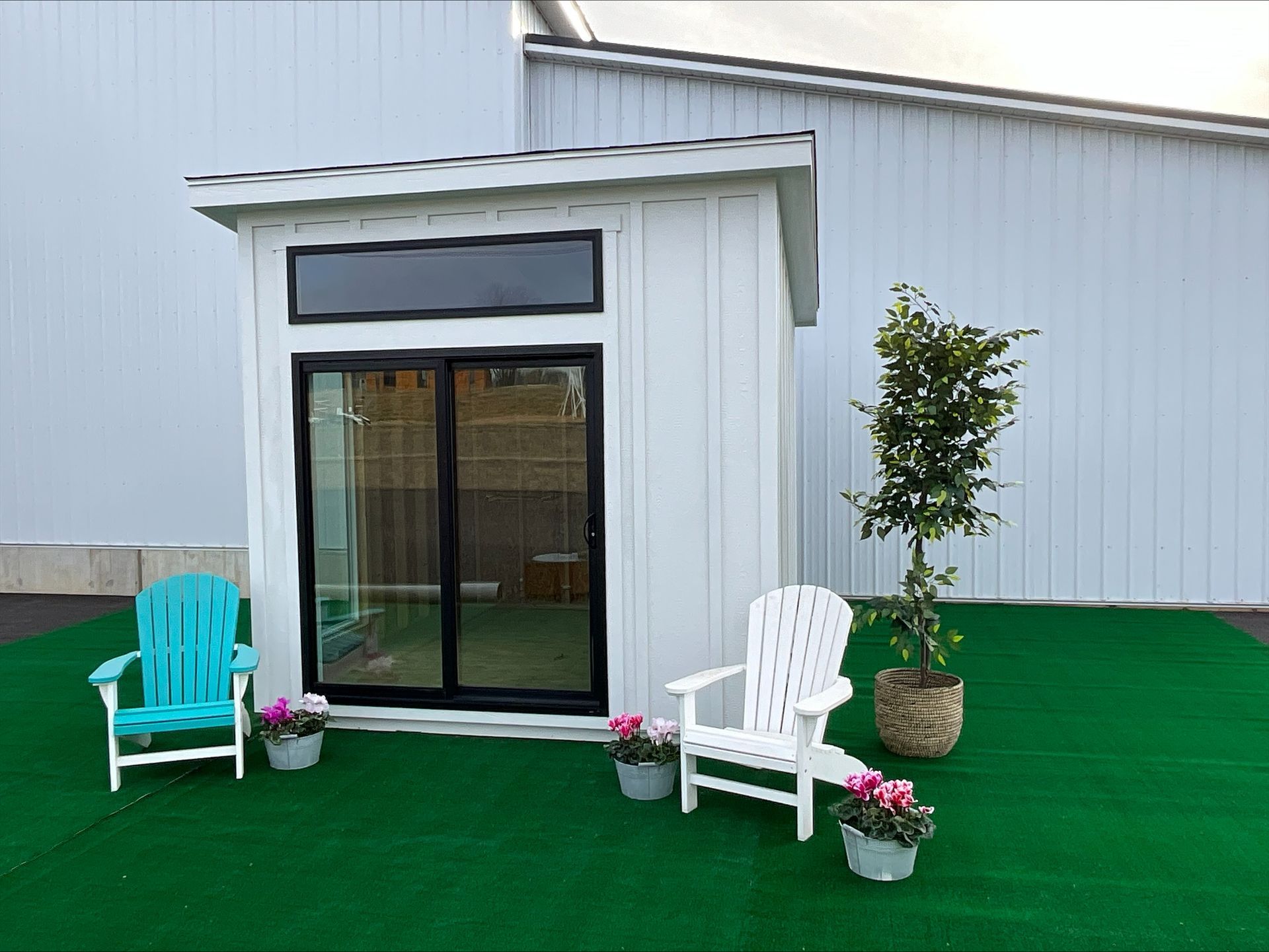 Lean-To white Studio Shed with black trim glass double doors, a black transom window, and a slanted roof.