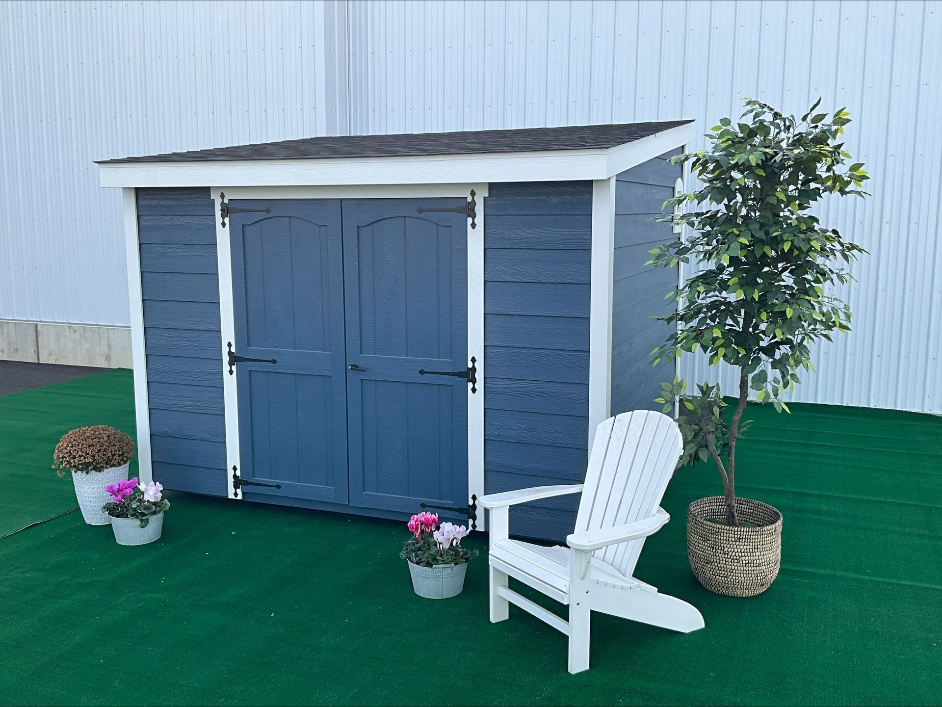 Blue Lean-To shed with white trim, blue double doors, and a slanted dark-colored asphalt roof.
