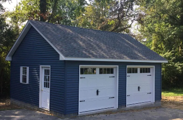 blue detached garage with two white garage doors and one regular white door on the side