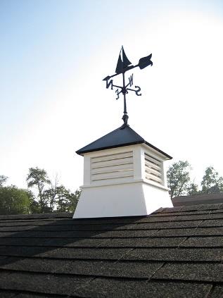 Close up of a black sailboat weathervane on top of a white cupola