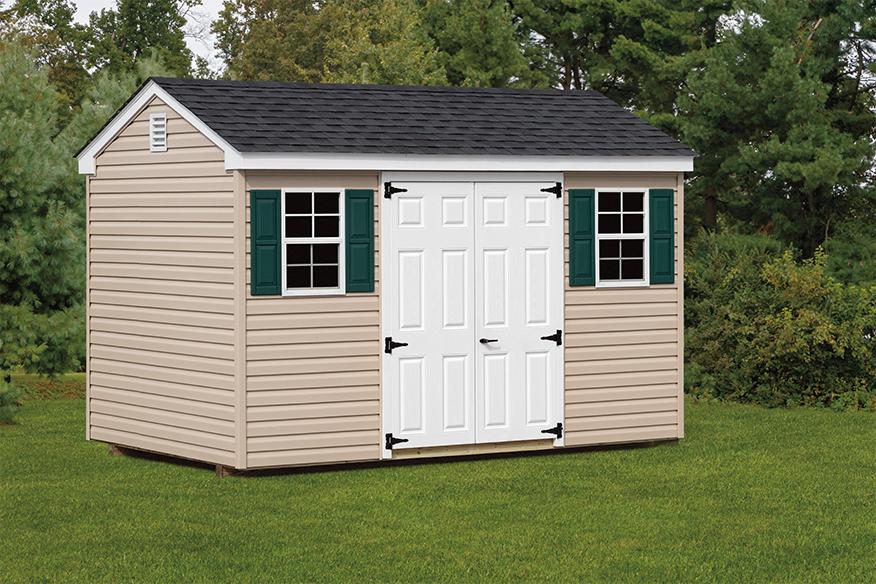 Tan shed with white double doors, 2 windows with green shutters, white trim, and a black roof