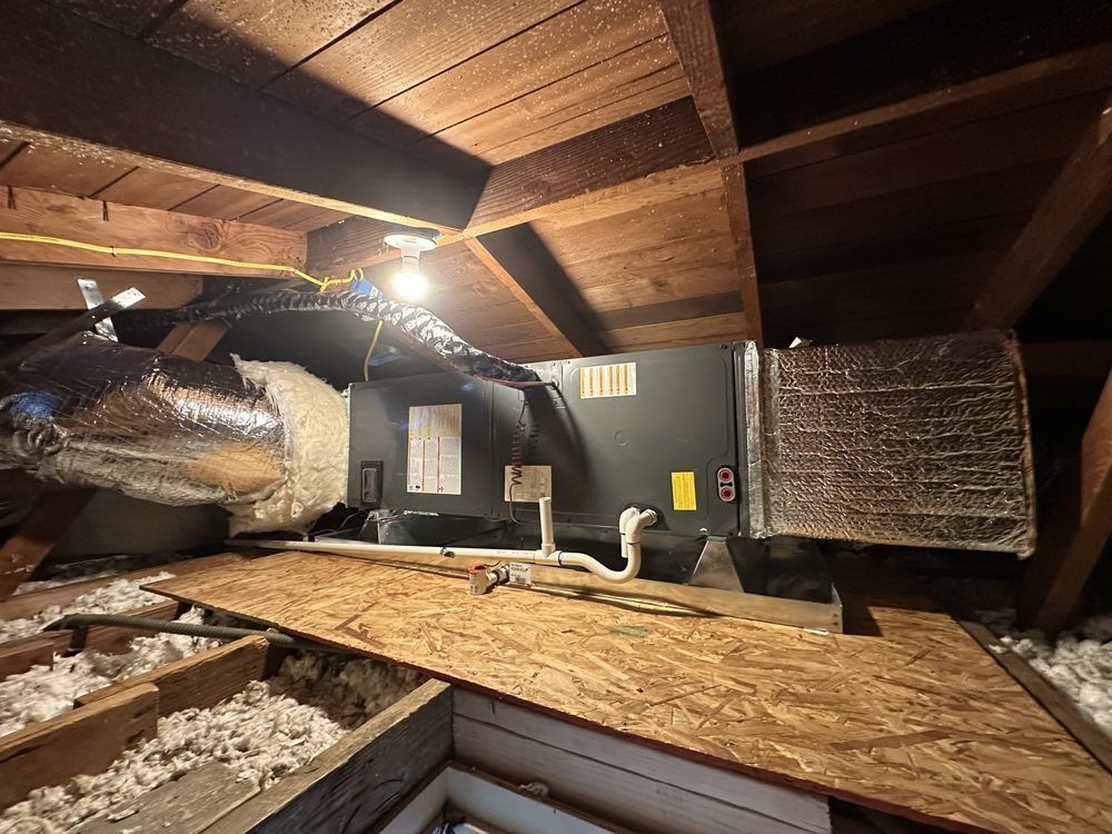 HVAC unit in an attic, with ductwork and wooden beams. Brown, gray, and white colors.