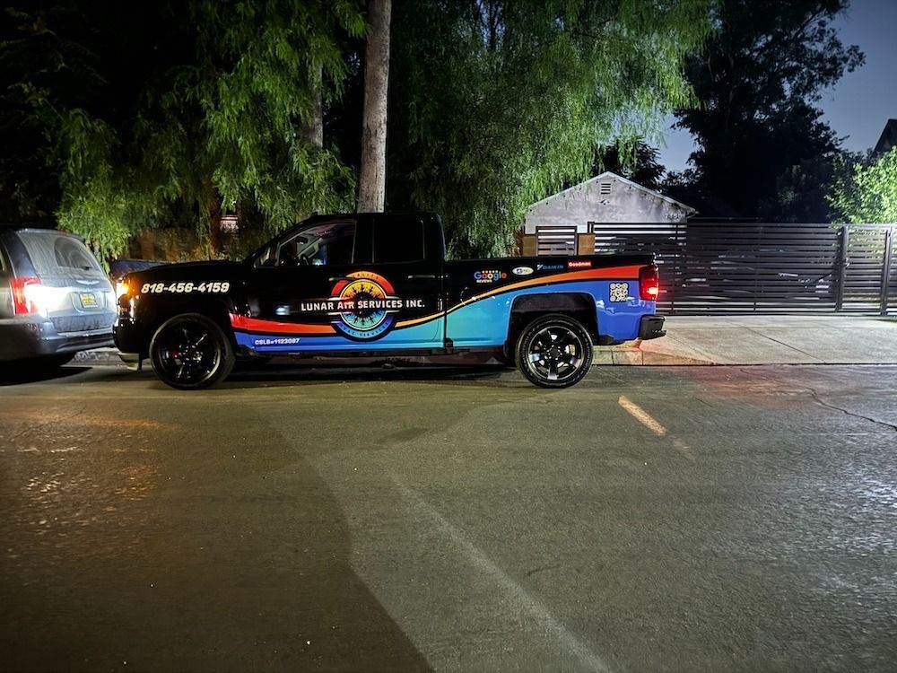 Black pickup truck with colorful logo parked on a street at night.