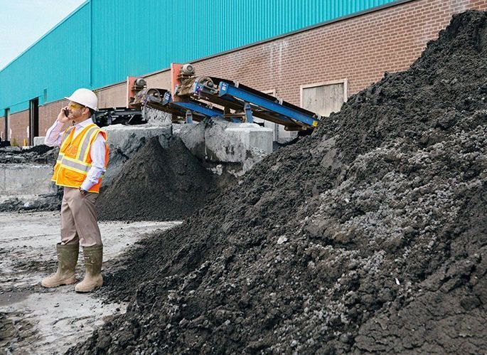 Employee surrounded by huge piles of recycled soil