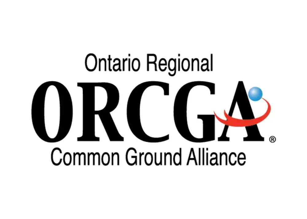 Two people in safety vests and hard hats looking at a tablet outdoors.