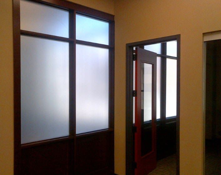 A hallway with a red door and frosted glass windows