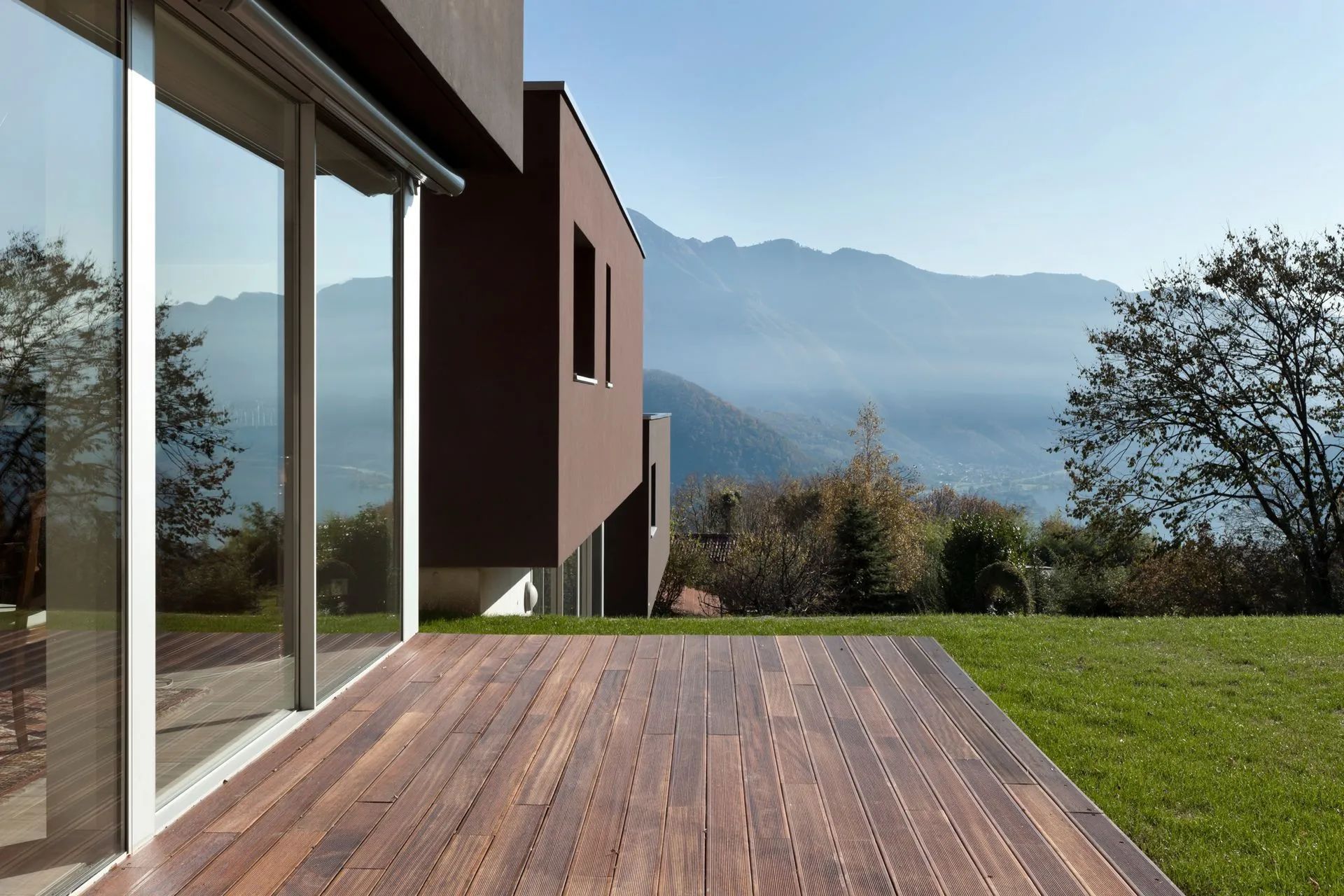 Modern house with wooden deck overlooking mountains and trees