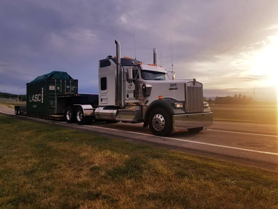 Un semi-camion roule sur une autoroute au coucher du soleil.