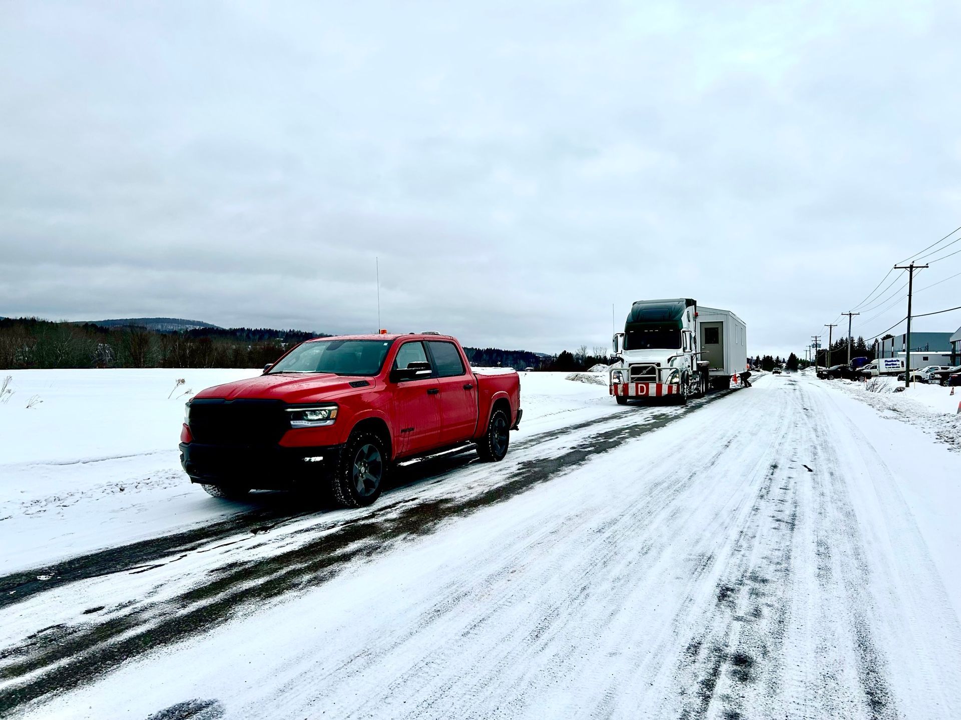 Un camion rouge roule sur une route enneigée.