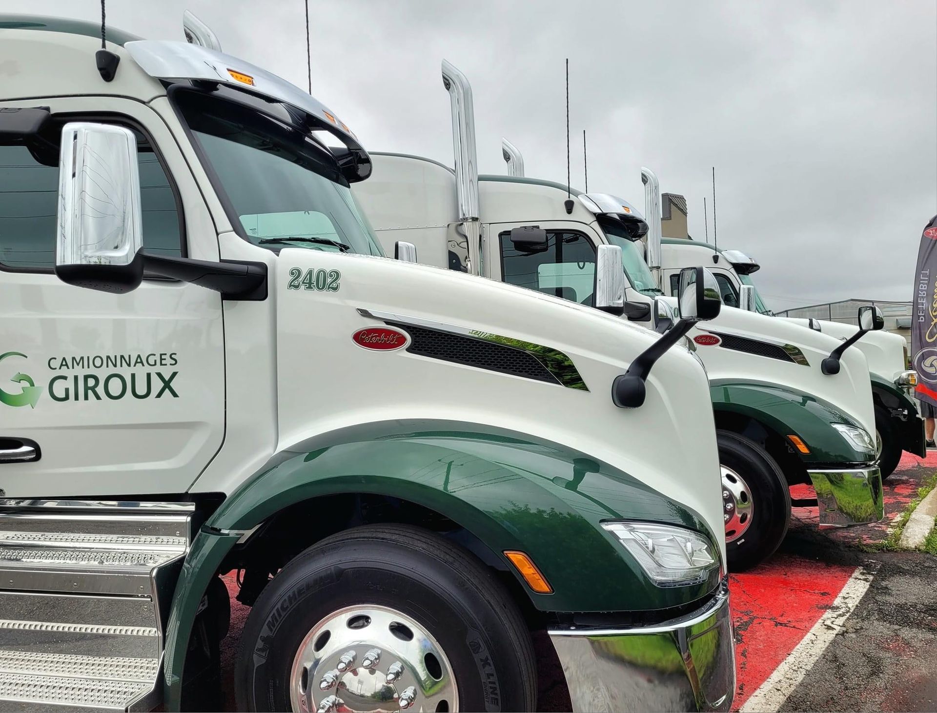 A row of semi trucks are parked in a parking lot.
