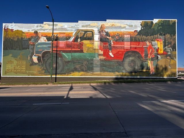 A large mural on the side of a building shows a red truck