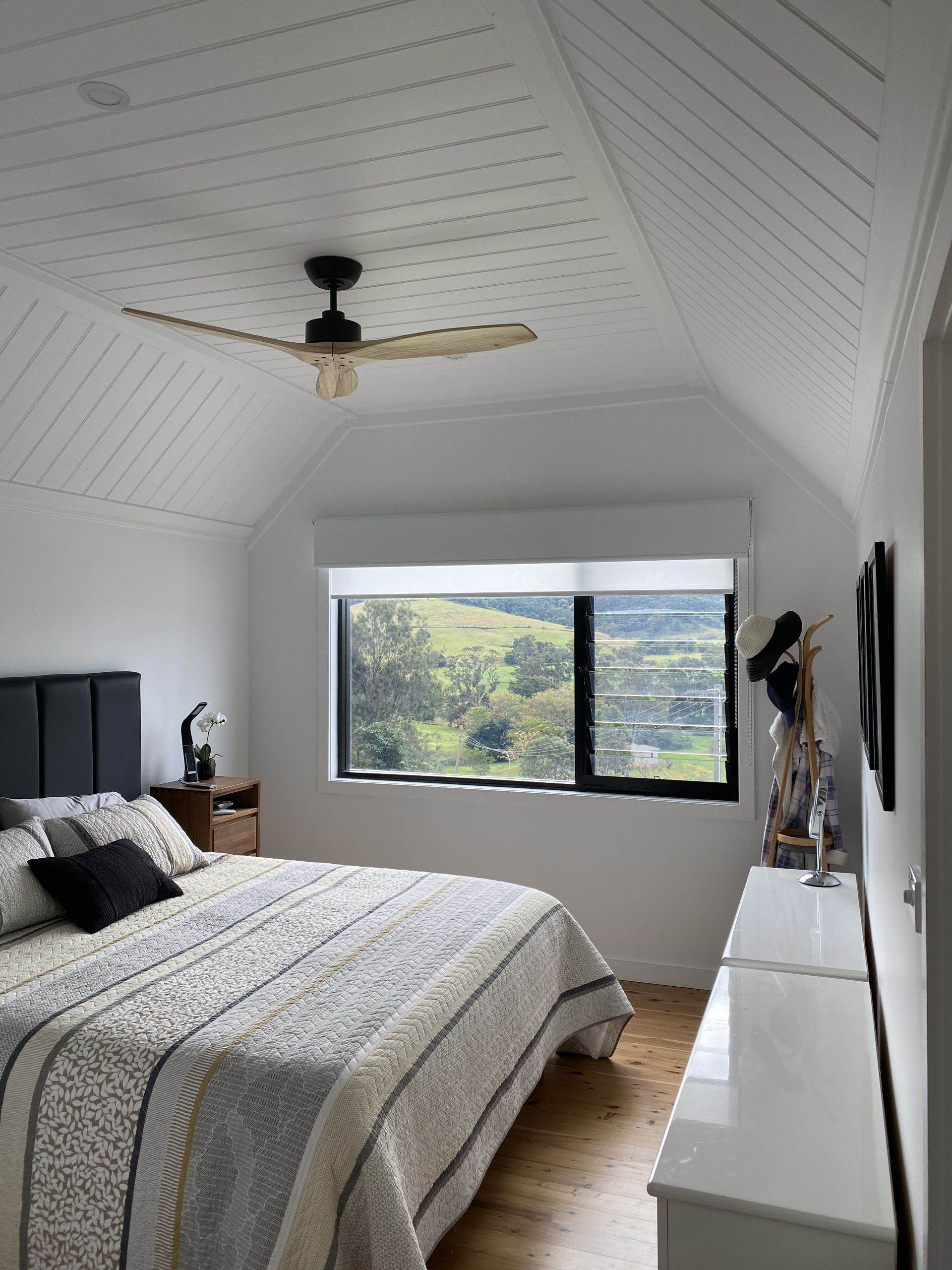Bedroom With White Sloped Ceiling, Bed, Window With a View of a Green Hill — DG Electrical & Fire In Kiama, NSW