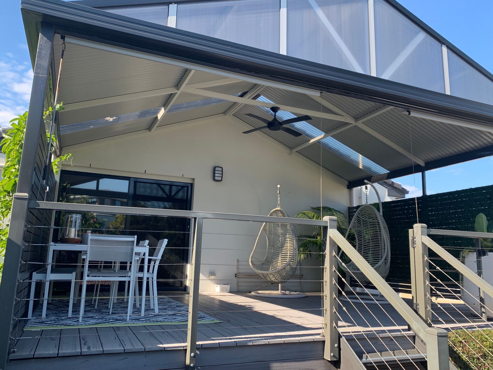 Outdoor Deck With Dining Set, Hanging Chairs, and a Sloped Roof Patio — DG Electrical & Fire In Kiama, NSW