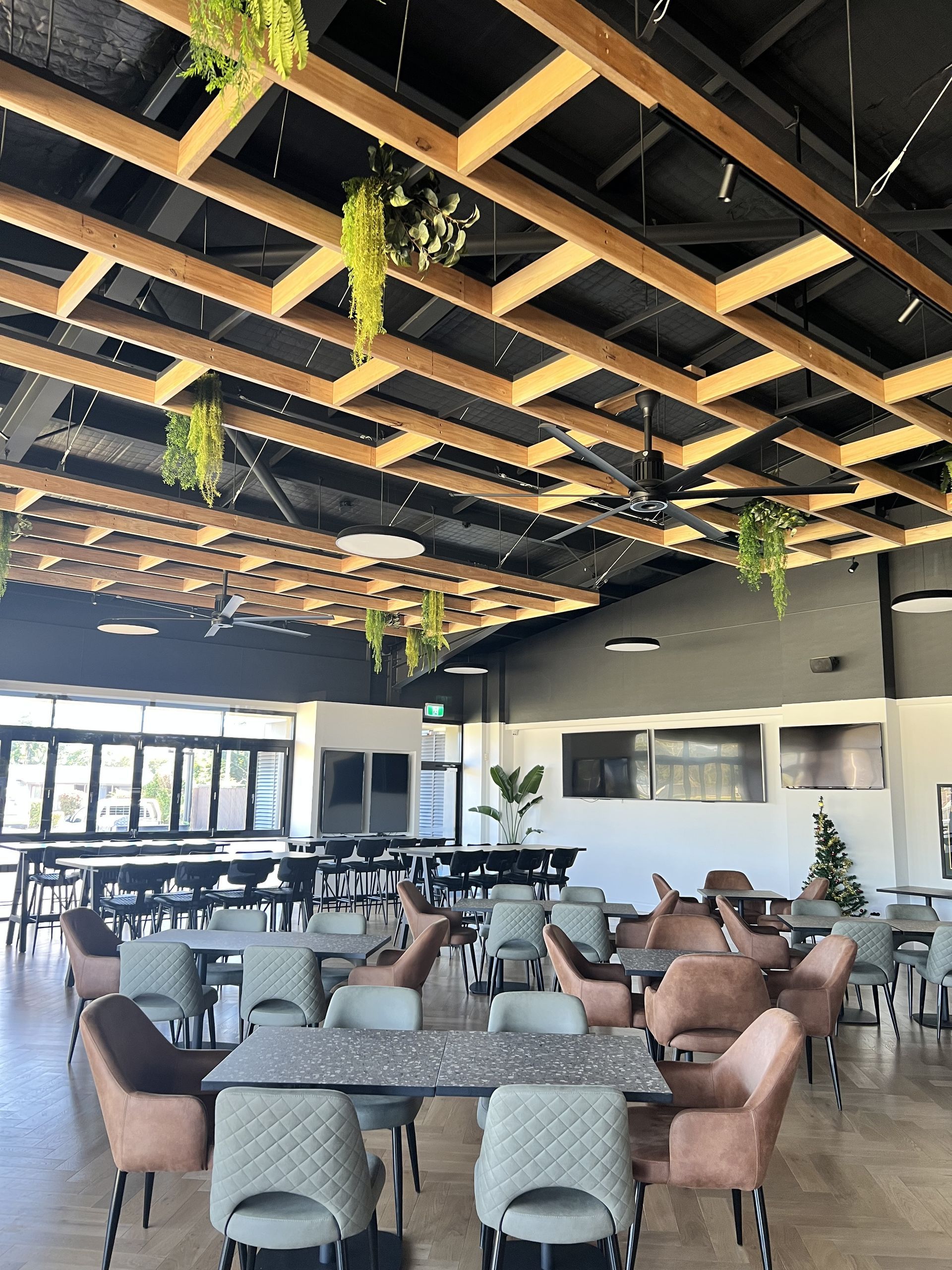 Restaurant interior with tables, chairs, and a wooden beam ceiling with hanging plants. — DG Electrical & Fire In Kiama, NSW