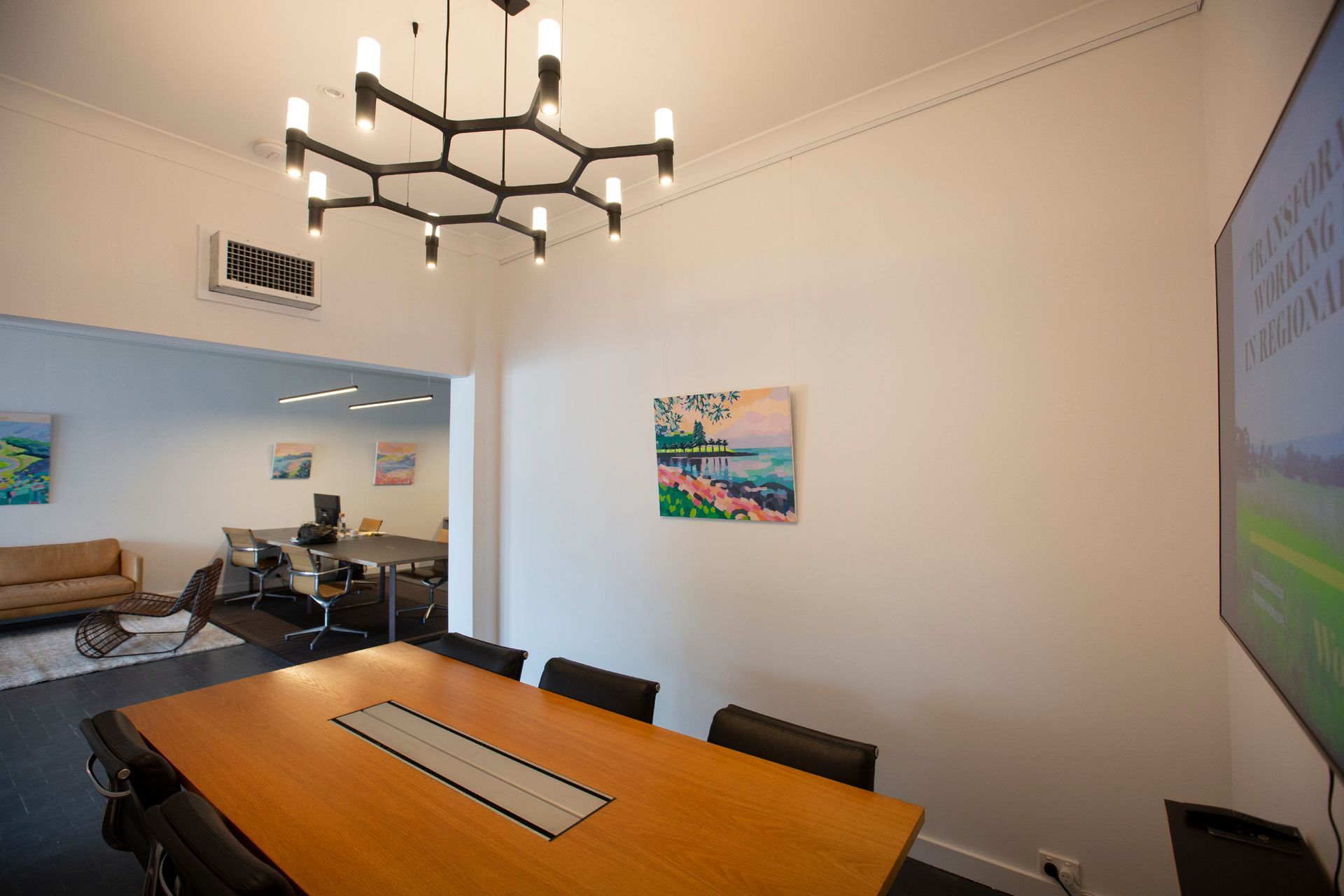 Conference room with a large wooden table, art, and a unique chandelier. — DG Electrical & Fire In Kiama, NSW