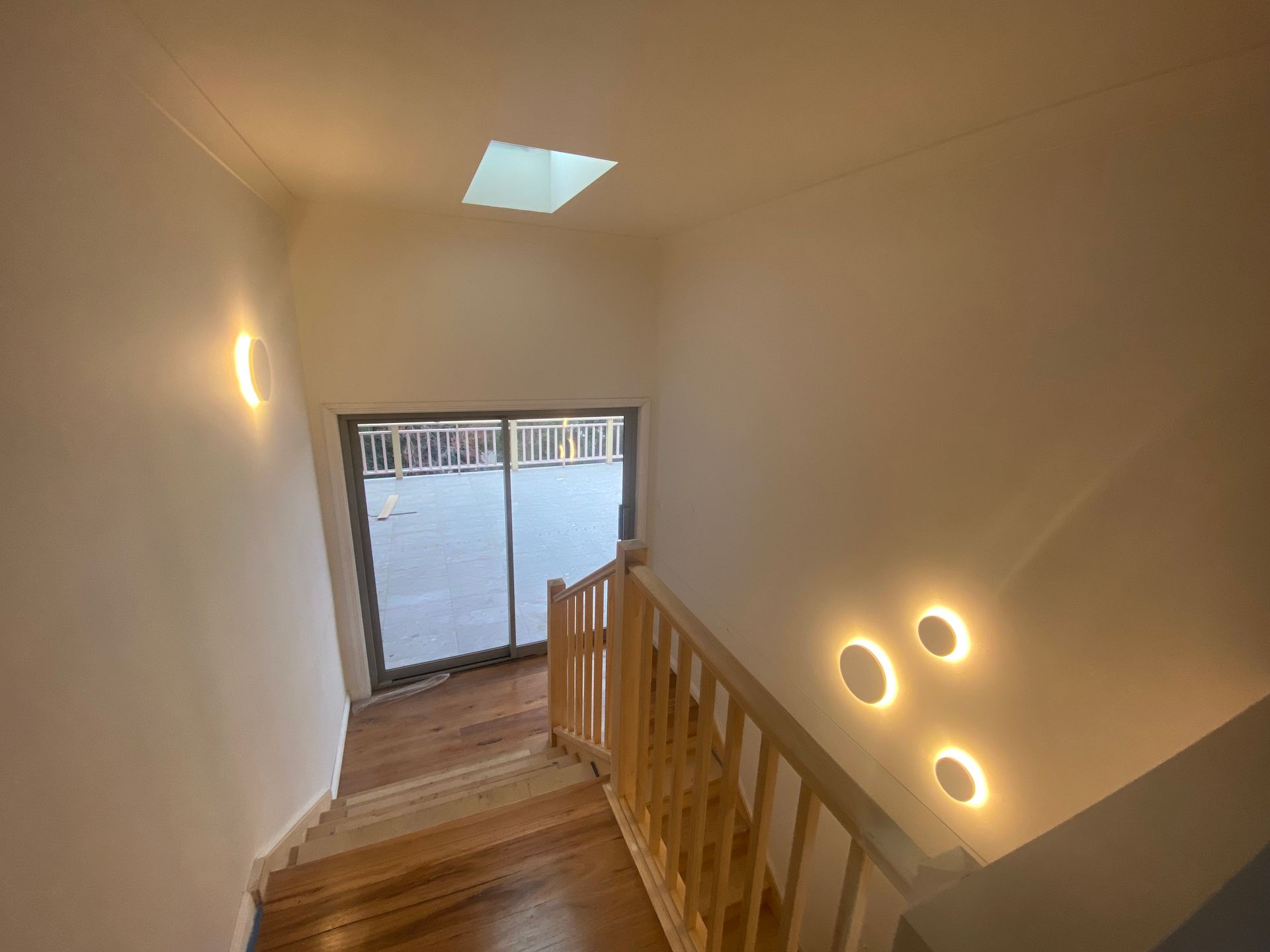 Staircase With Wooden Steps and Railing. Bright Wall Lights Illuminate a Hallway — DG Electrical & Fire In Kiama, NSW