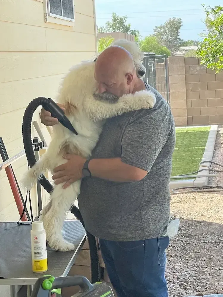 A man is holding a large white dog in his arms.