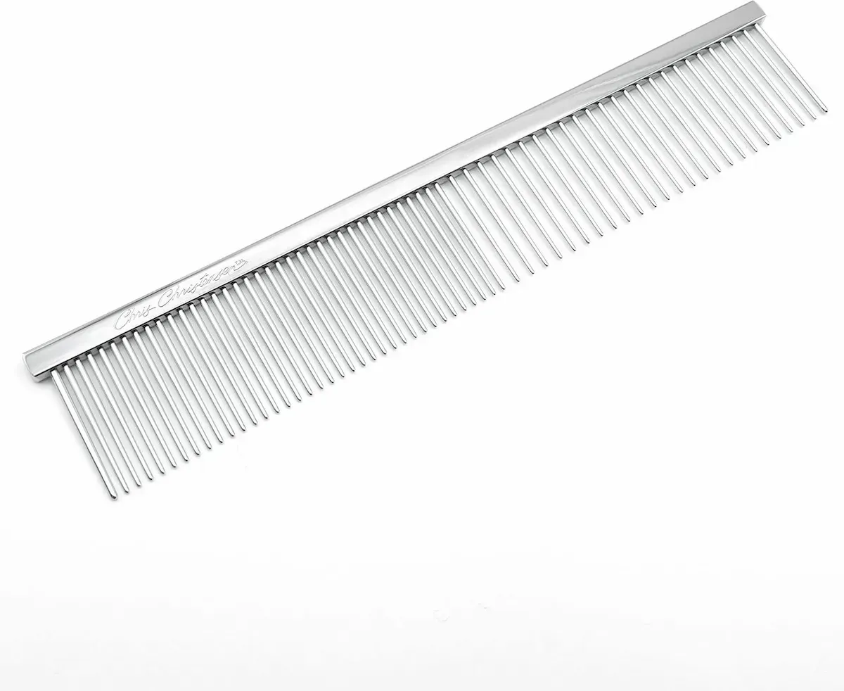 A close up of a stainless steel comb on a white background.
