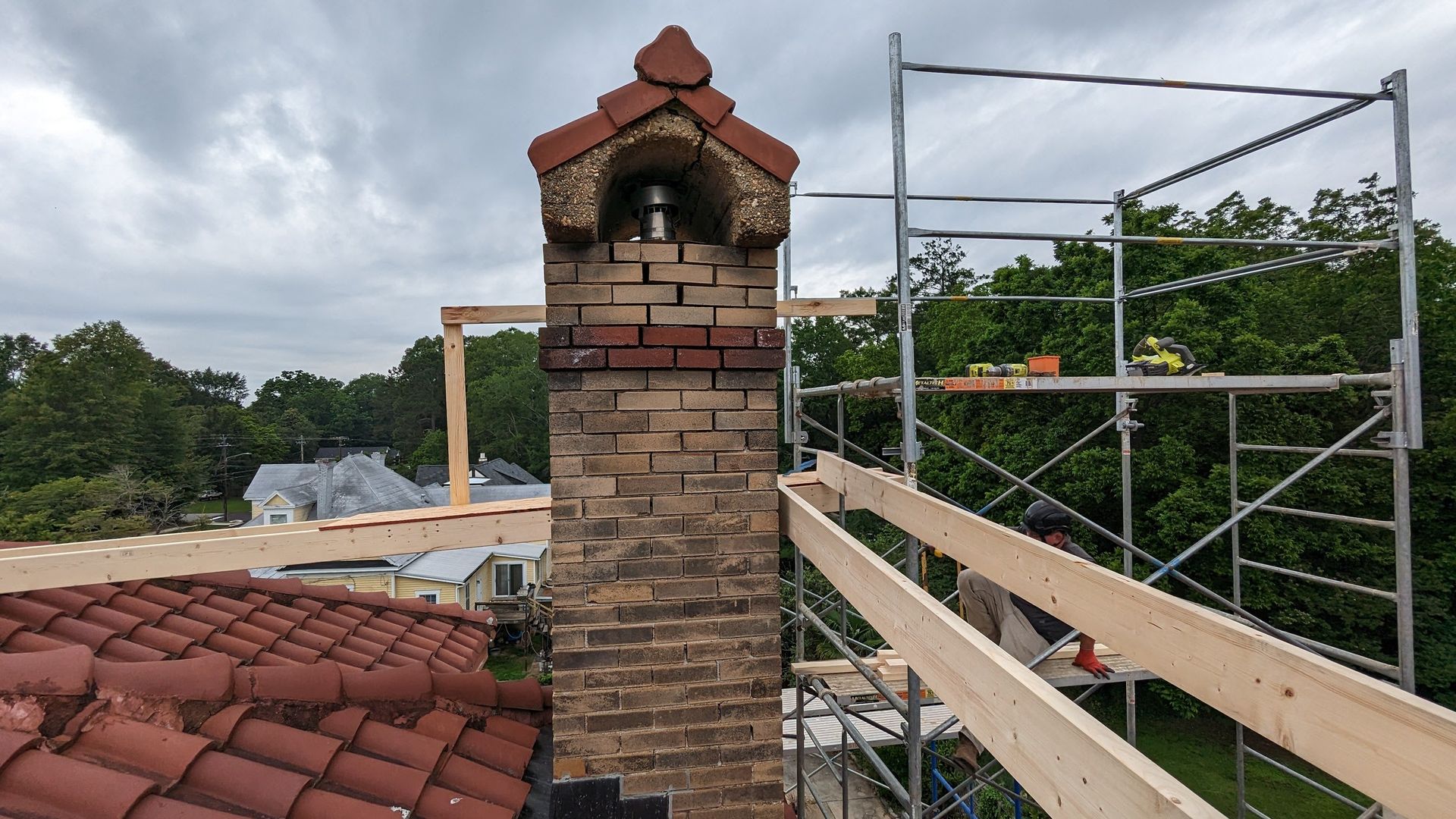 A brick chimney on top of a roof with scaffolding around it.