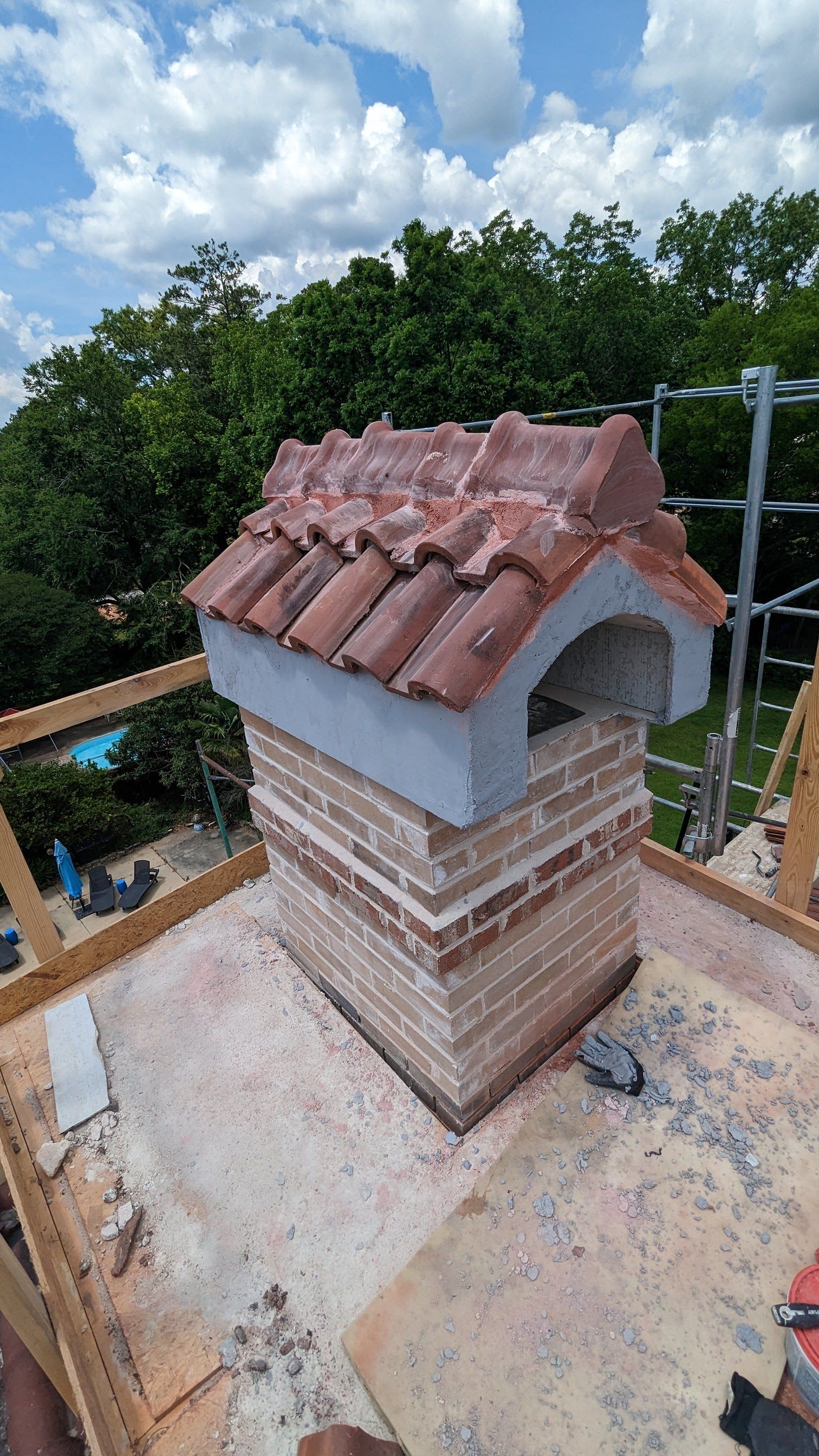 A brick chimney with a tiled roof is sitting on top of a roof.
