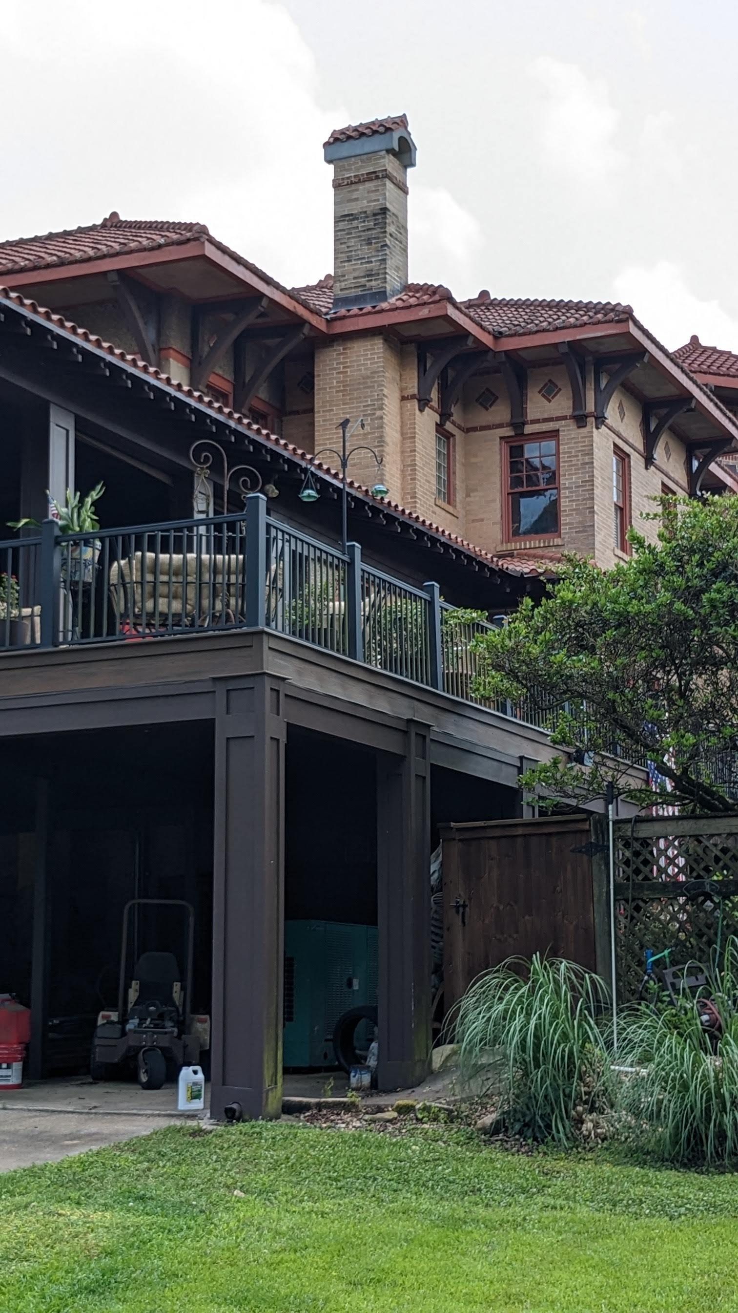 A large house with a balcony and a chimney is sitting on top of a lush green field.