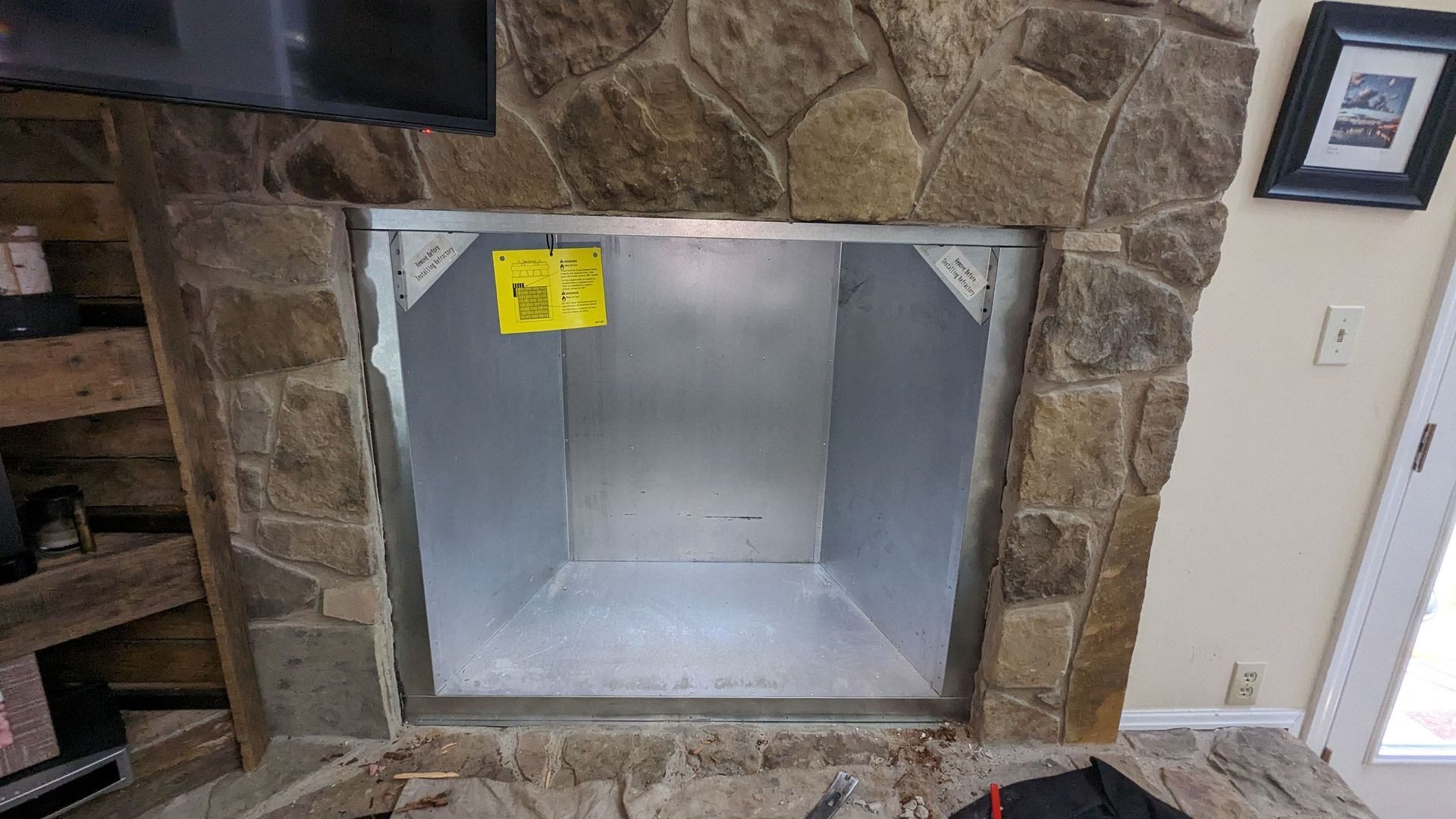 A fireplace is being built into a stone wall in a living room.