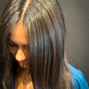 Woman with long, straight brown hair, looking down. Lit from above.