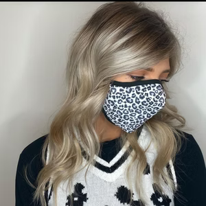 Woman wearing a leopard-print face mask, with blonde wavy hair, and a black and white sweater.