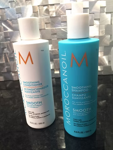 Two bottles of Moroccanoil Smoothing Shampoo and Conditioner. White and turquoise bottles with white caps.