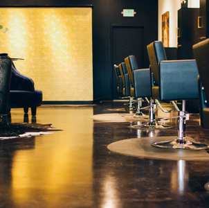 Salon interior with dark walls, gold accent wall, and chairs.