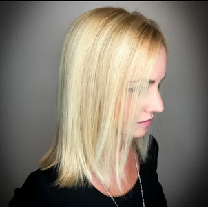 Blonde hair, shoulder-length, styled sleekly. Woman in black top, soft lighting.