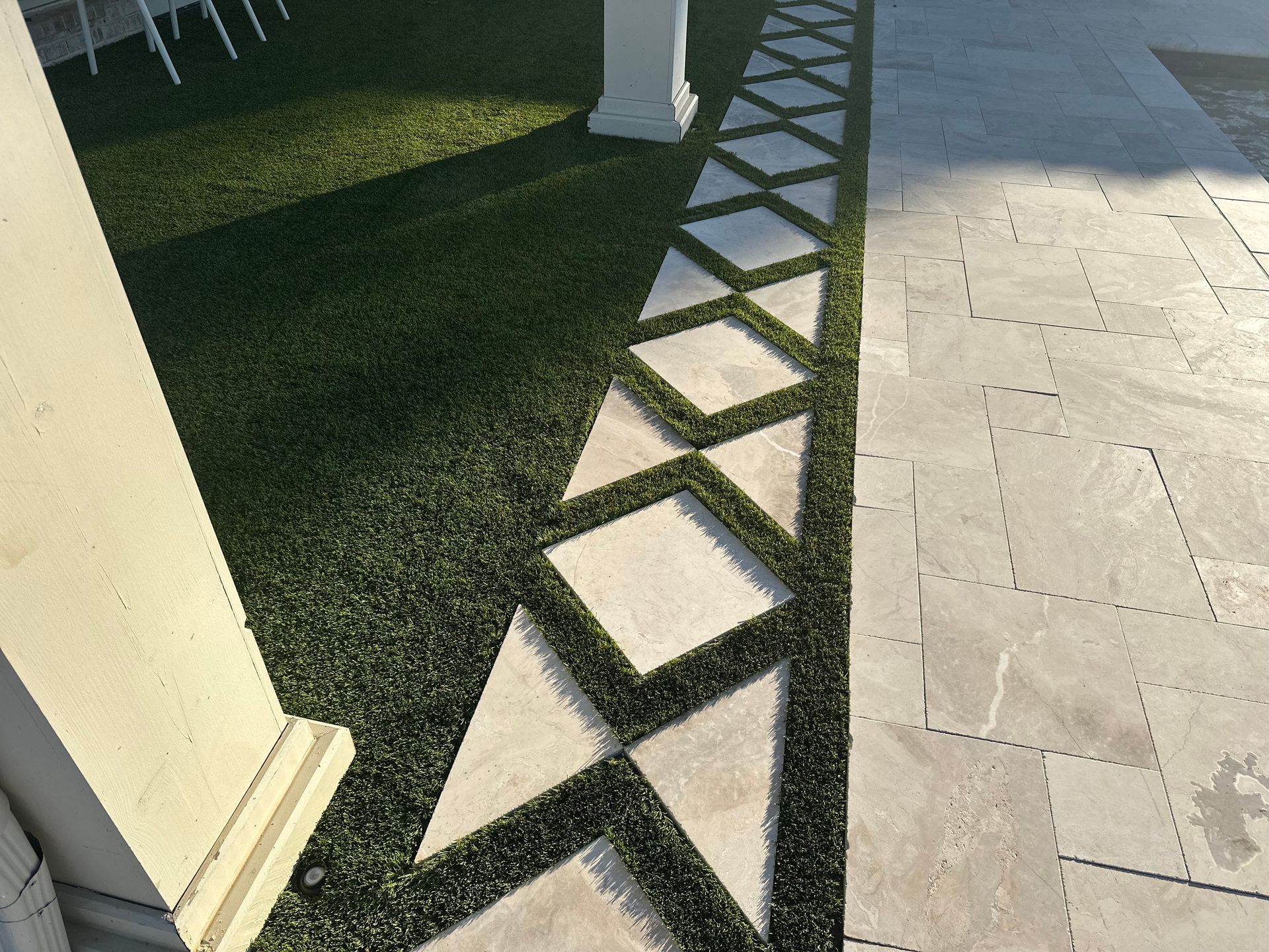 Artificial turf and square stone walkway with a geometric pattern.