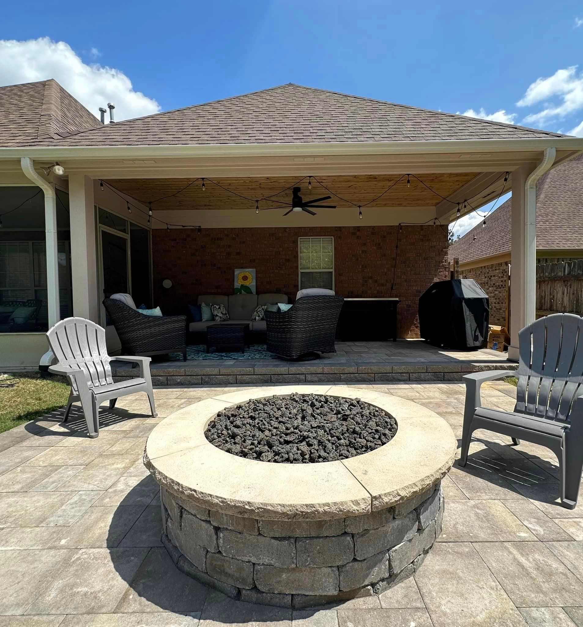 Patio with fire pit, seating, and covered area with brick wall.