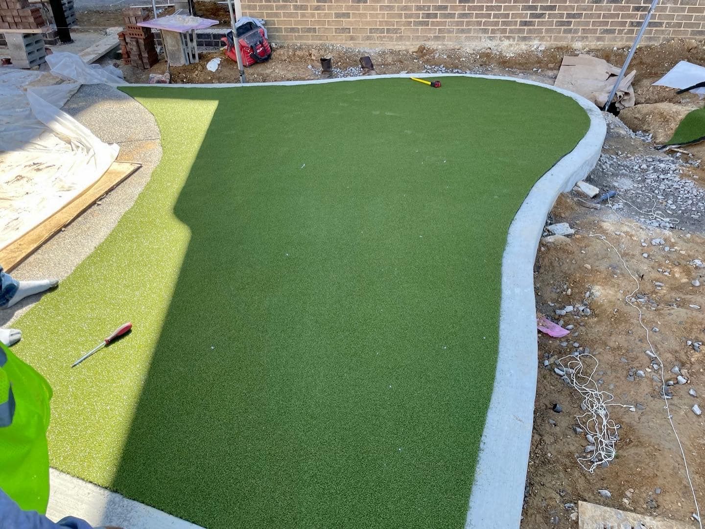 Green artificial turf installation with white concrete border.