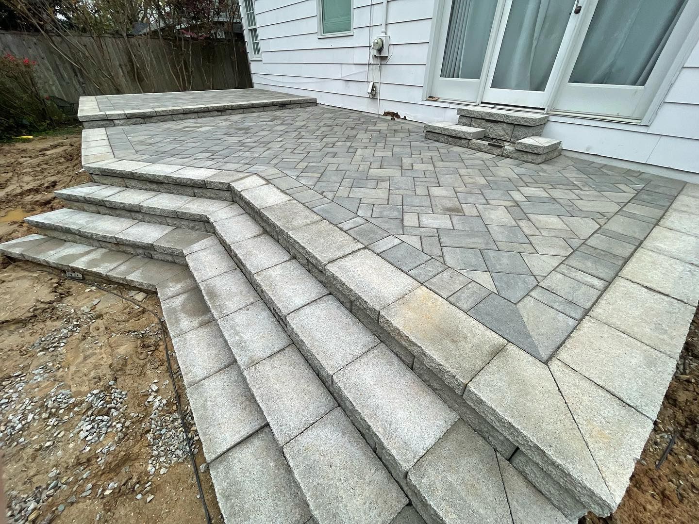 Gray stone patio and steps outside a white building.