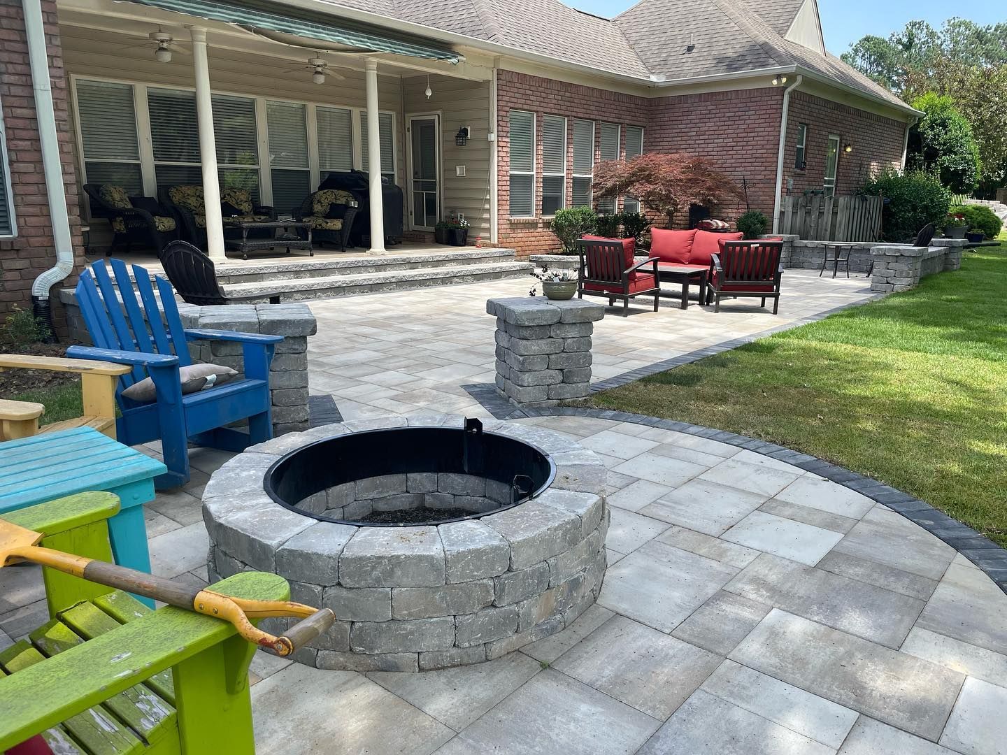 Patio with fire pit, seating, and brick home in background.