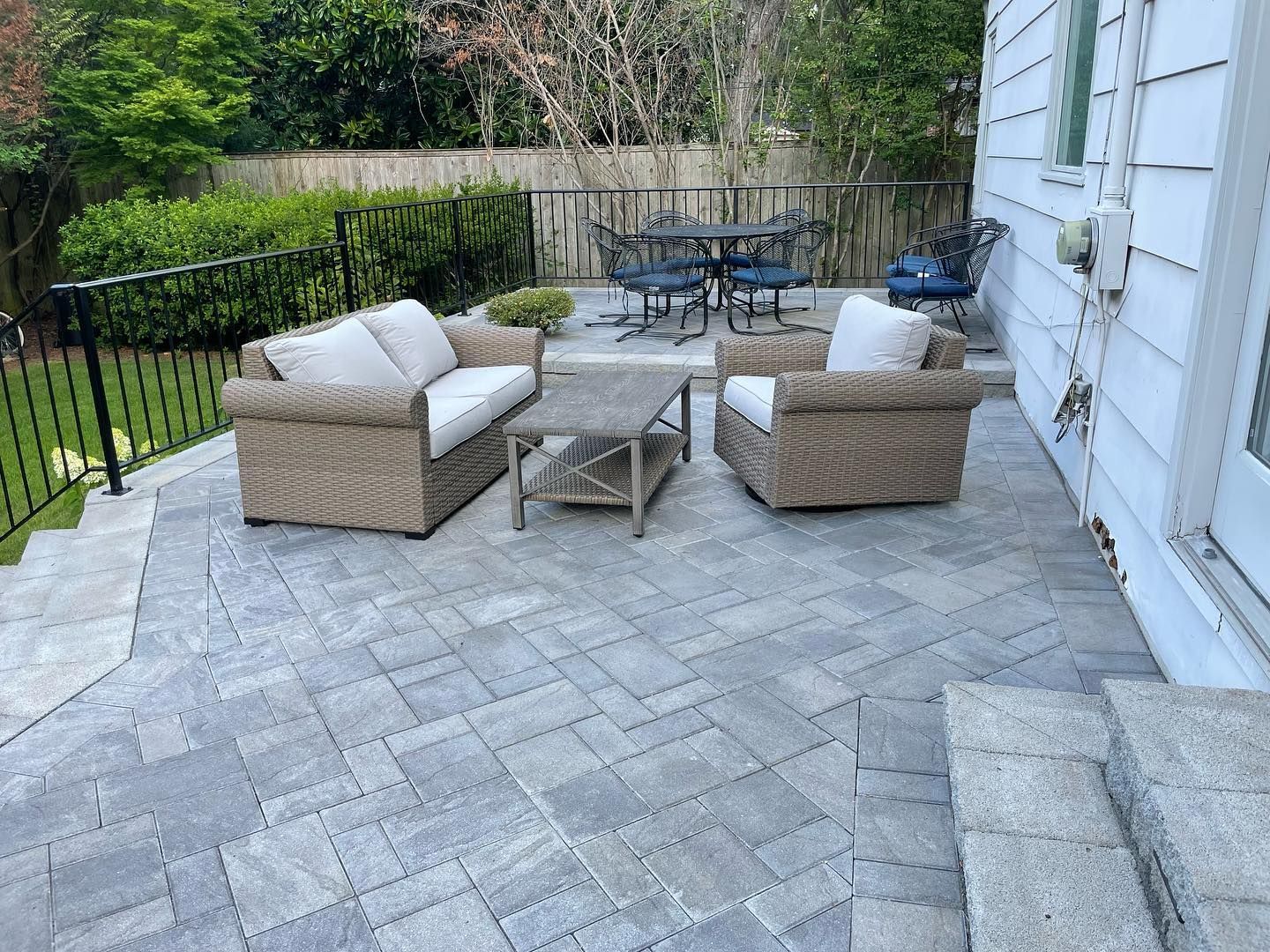 Outdoor patio with gray brick paving, seating area, and dining table.