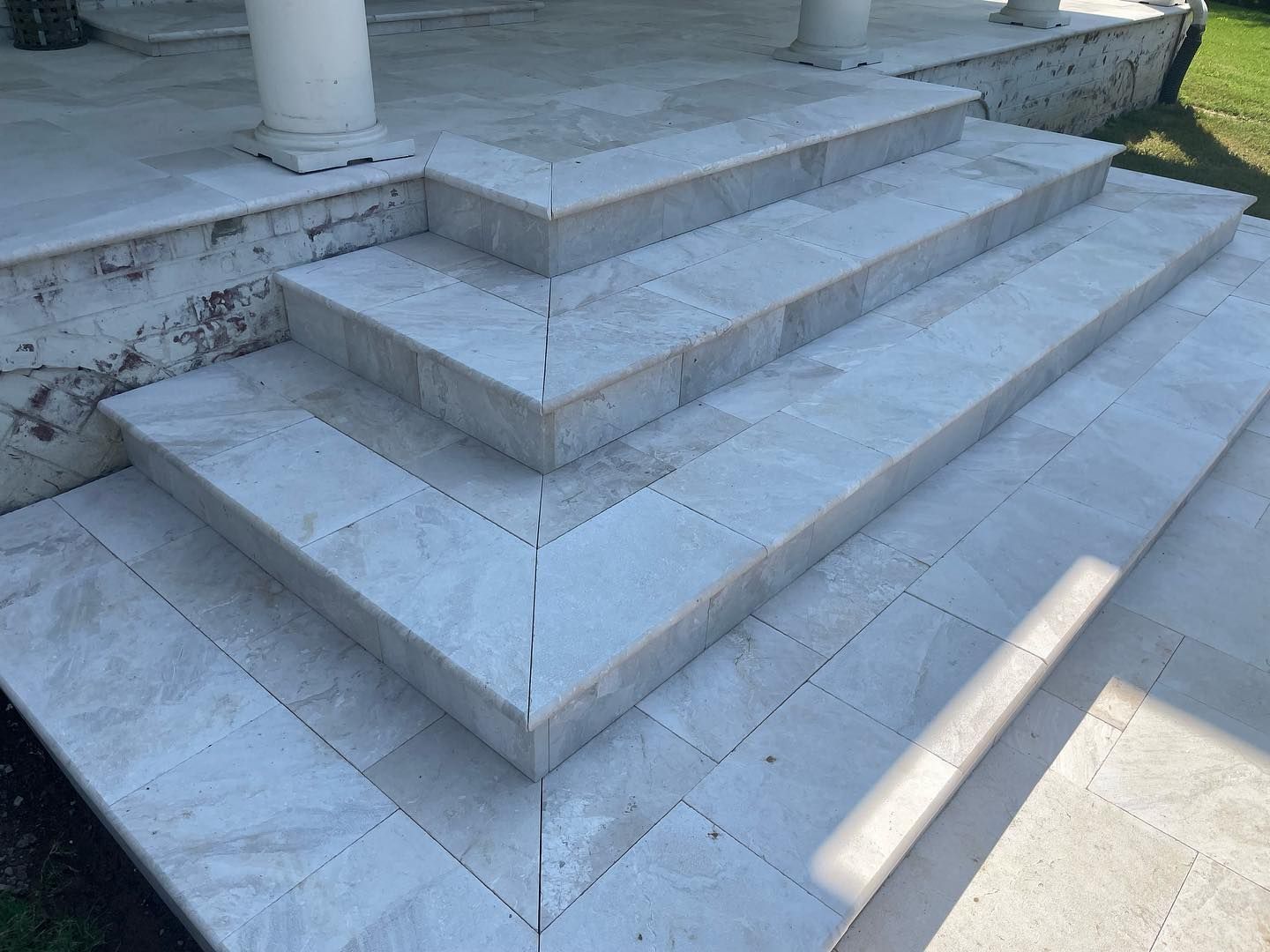 Stone steps leading up to a building with columns; light gray color.