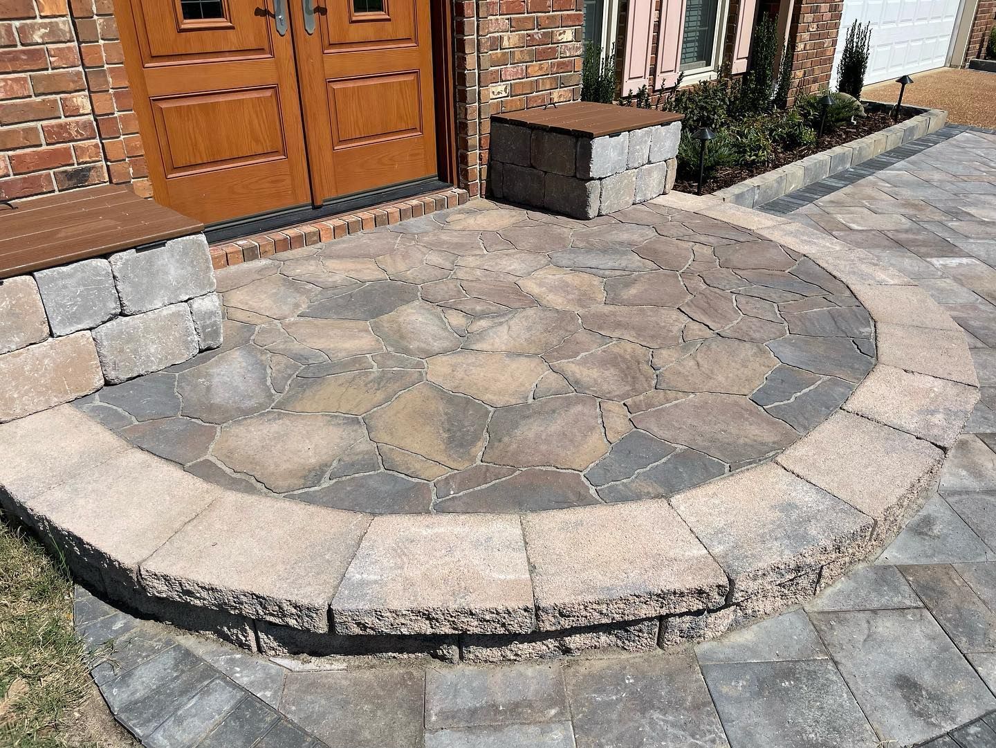 Stone entryway with brick house, circular patio, and low retaining wall.