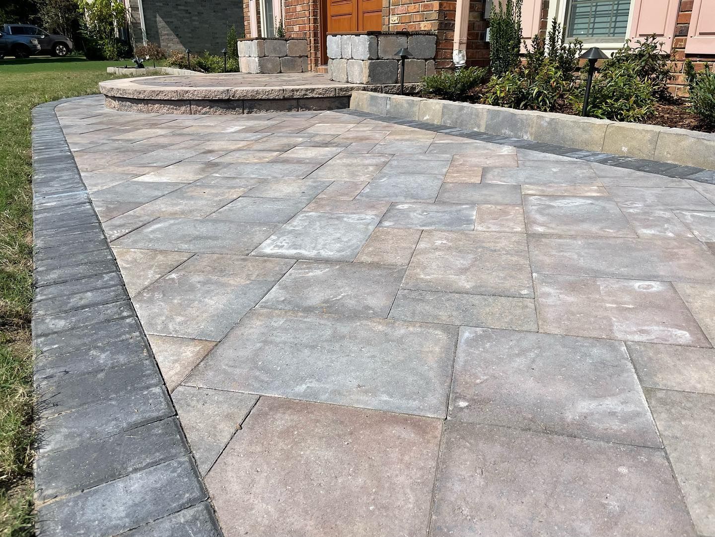 Brick patio with gray and tan pavers leading to a building's entrance.